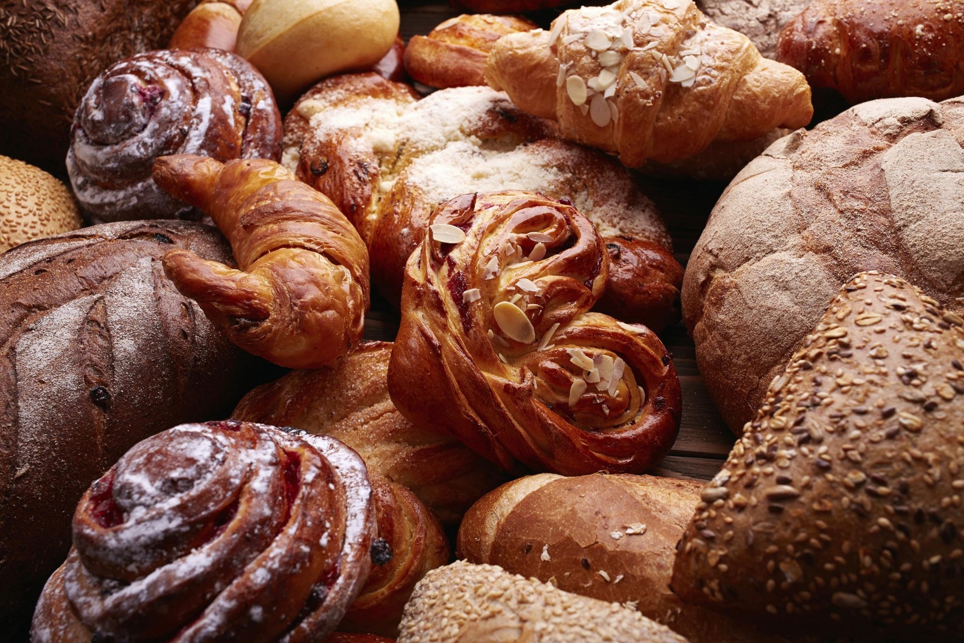 HD desktop wallpaper featuring an assortment of freshly baked viennoiserie, including croissants and various breads, showcasing rich textures and golden crusts.