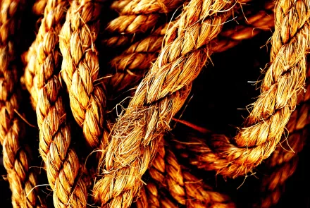 Close-up of intertwined, textured rope against a dark background, showcasing the intricate details of this man-made material. HD desktop wallpaper and background.