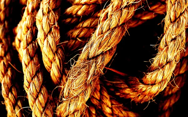 Close-up of intertwined, textured rope against a dark background, showcasing the intricate details of this man-made material. HD desktop wallpaper and background.