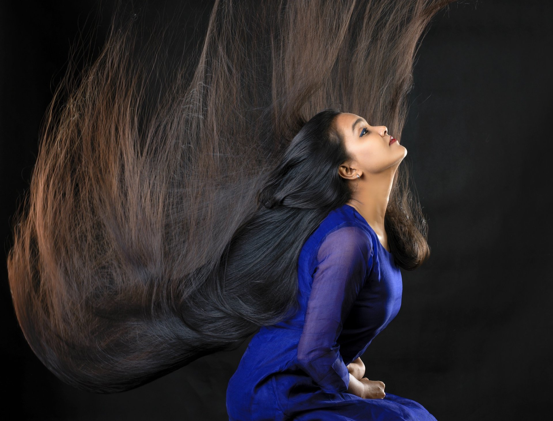 HD desktop wallpaper of a woman with long black hair wearing a flowing blue dress against a dark background.