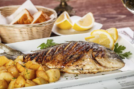 HD PC desktop wallpaper of a grilled whole fish with roasted potatoes, lemon wedges and crusty bread — a vibrant seafood, food, fish scene.