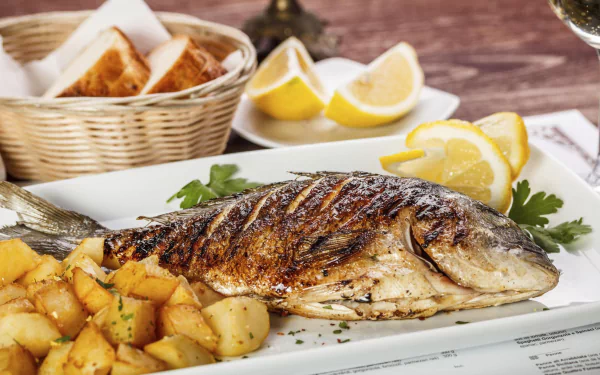 HD PC desktop wallpaper of a grilled whole fish with roasted potatoes, lemon wedges and crusty bread — a vibrant seafood, food, fish scene.