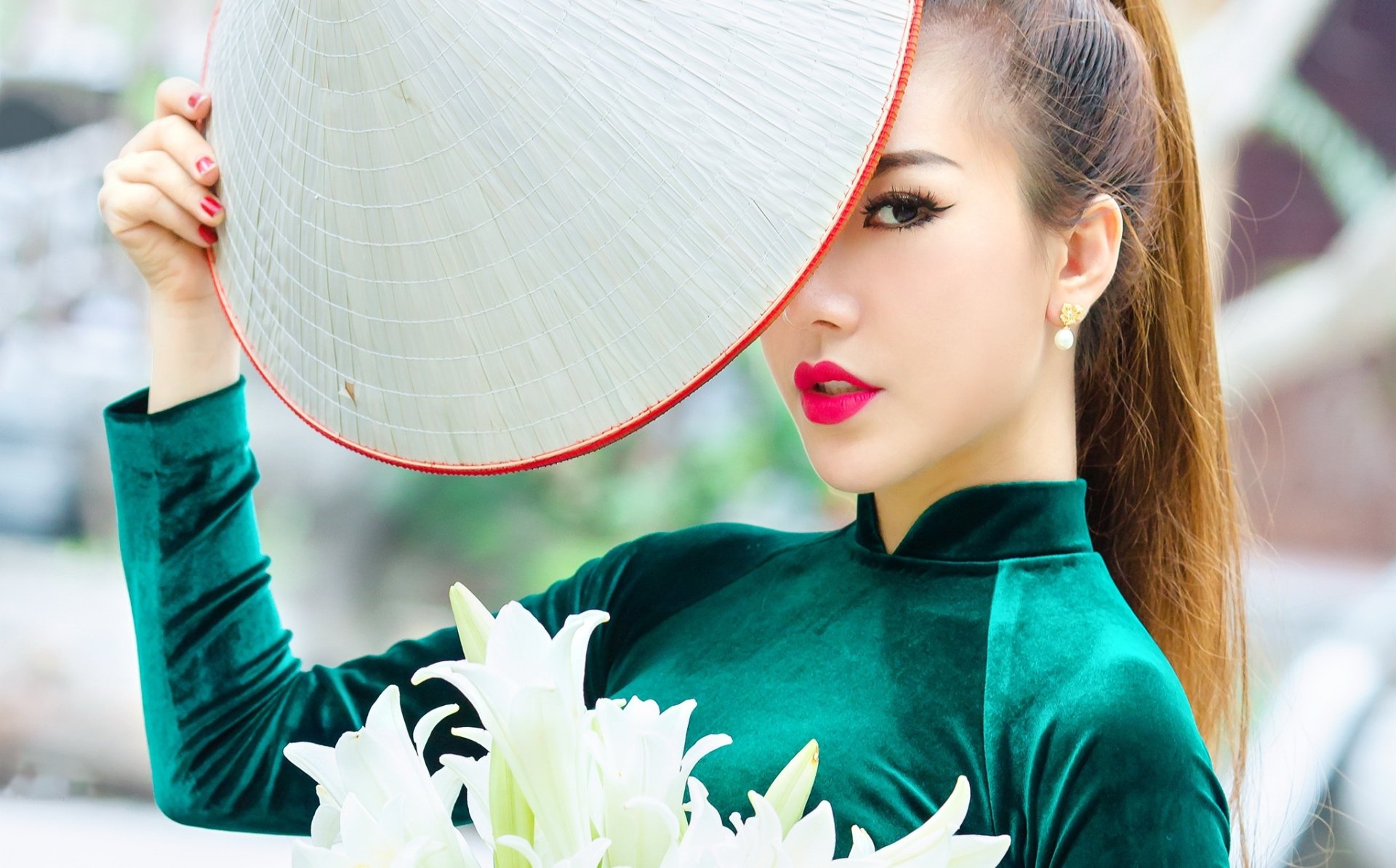 HD desktop wallpaper featuring an Asian woman with bold lipstick, wearing a traditional conical hat, holding white flowers, captured with a beautiful depth of field effect.