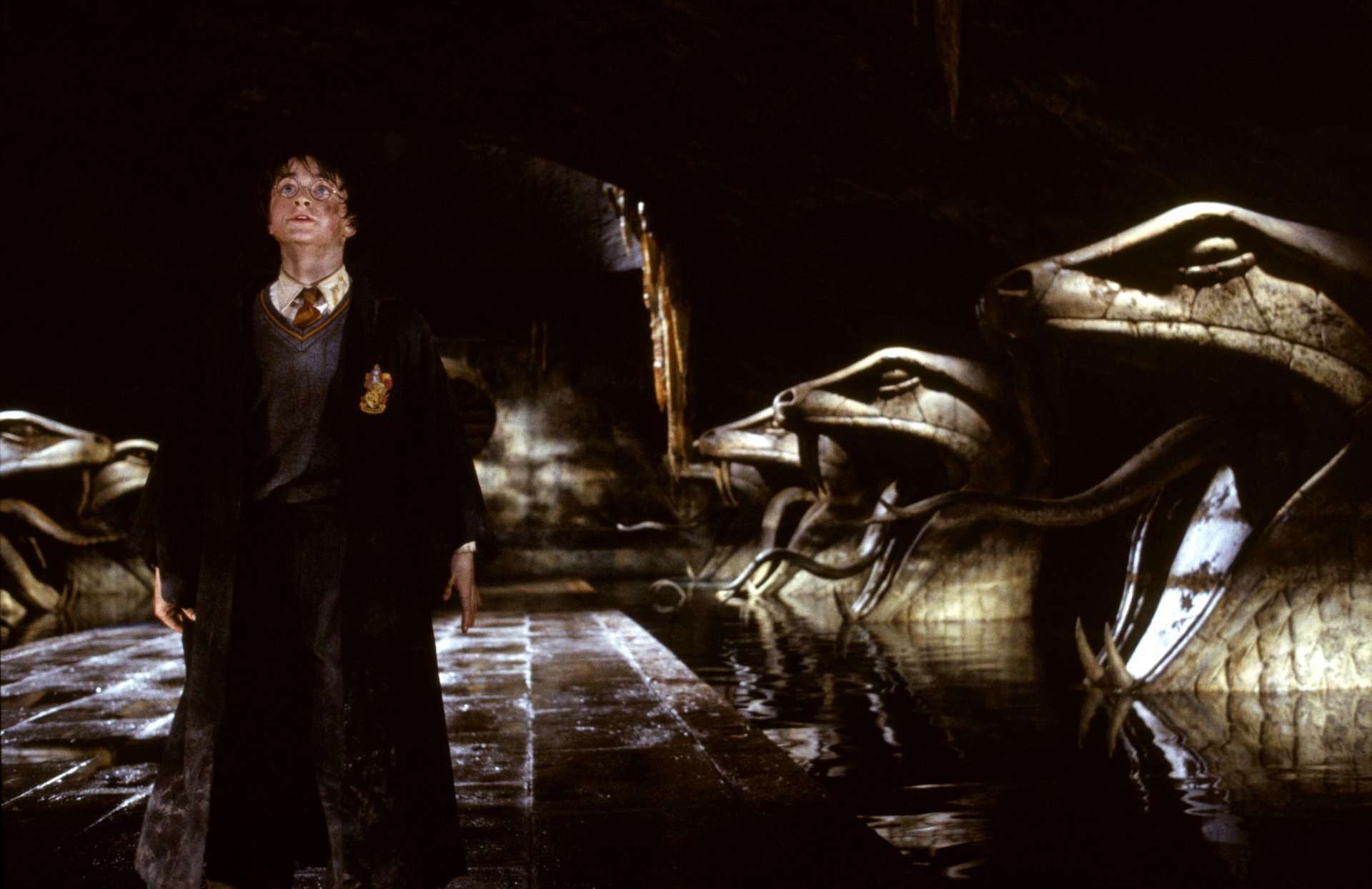 Harry Potter in the Chamber of Secrets, standing among giant serpent statues — cinematic scene rendered as a 2K Quad HD PC desktop wallpaper.