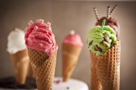 5K Ultra HD PC desktop wallpaper: close-up of assorted ice cream scoops in waffle cones — strawberry, mint‑chocolate, chocolate and vanilla with a soft blurred background.