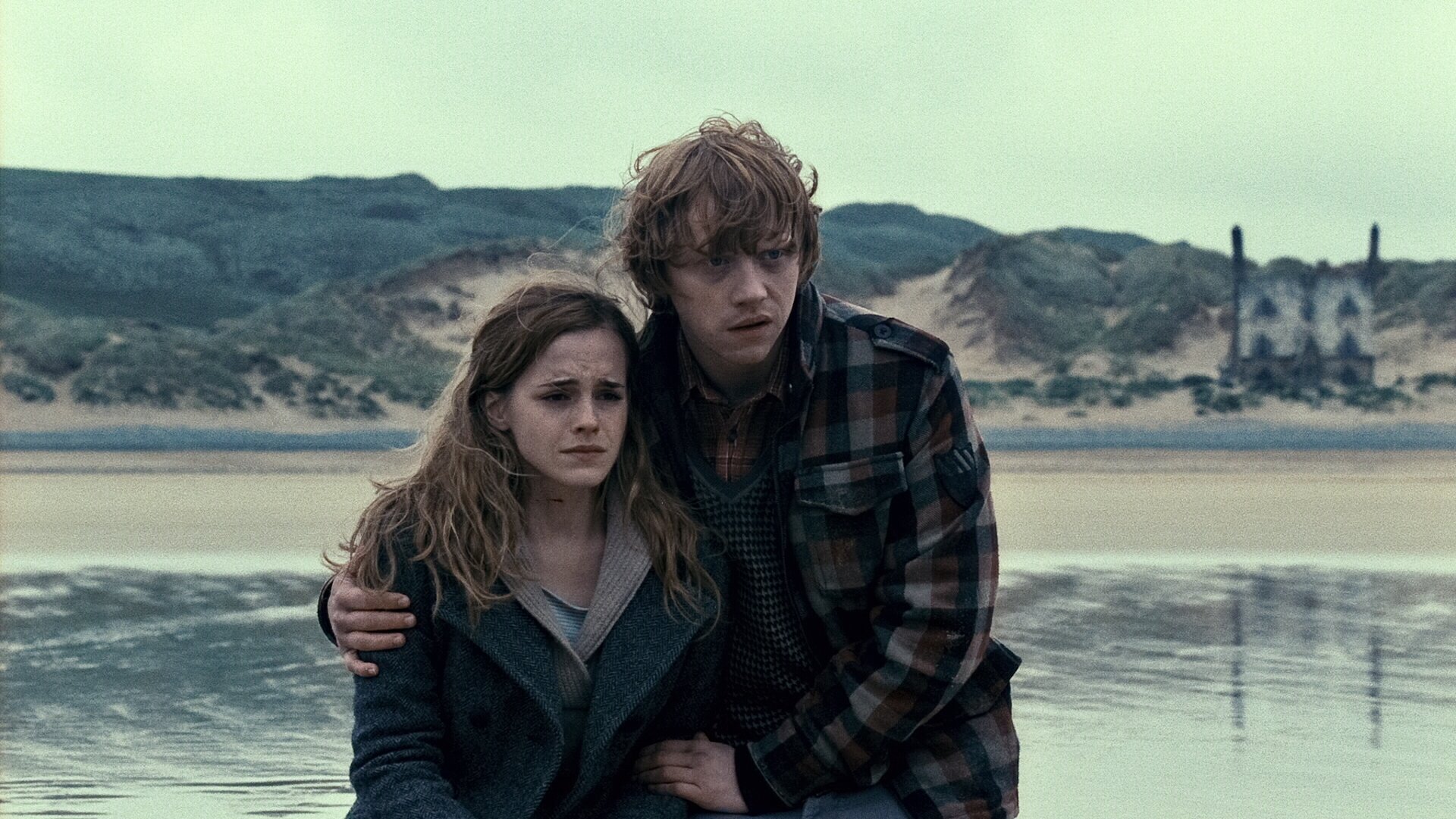 Hermione Granger and Ron Weasley from Harry Potter and the Deathly Hallows: Part 1 embrace on a windswept beach — HD PC desktop wallpaper and background.