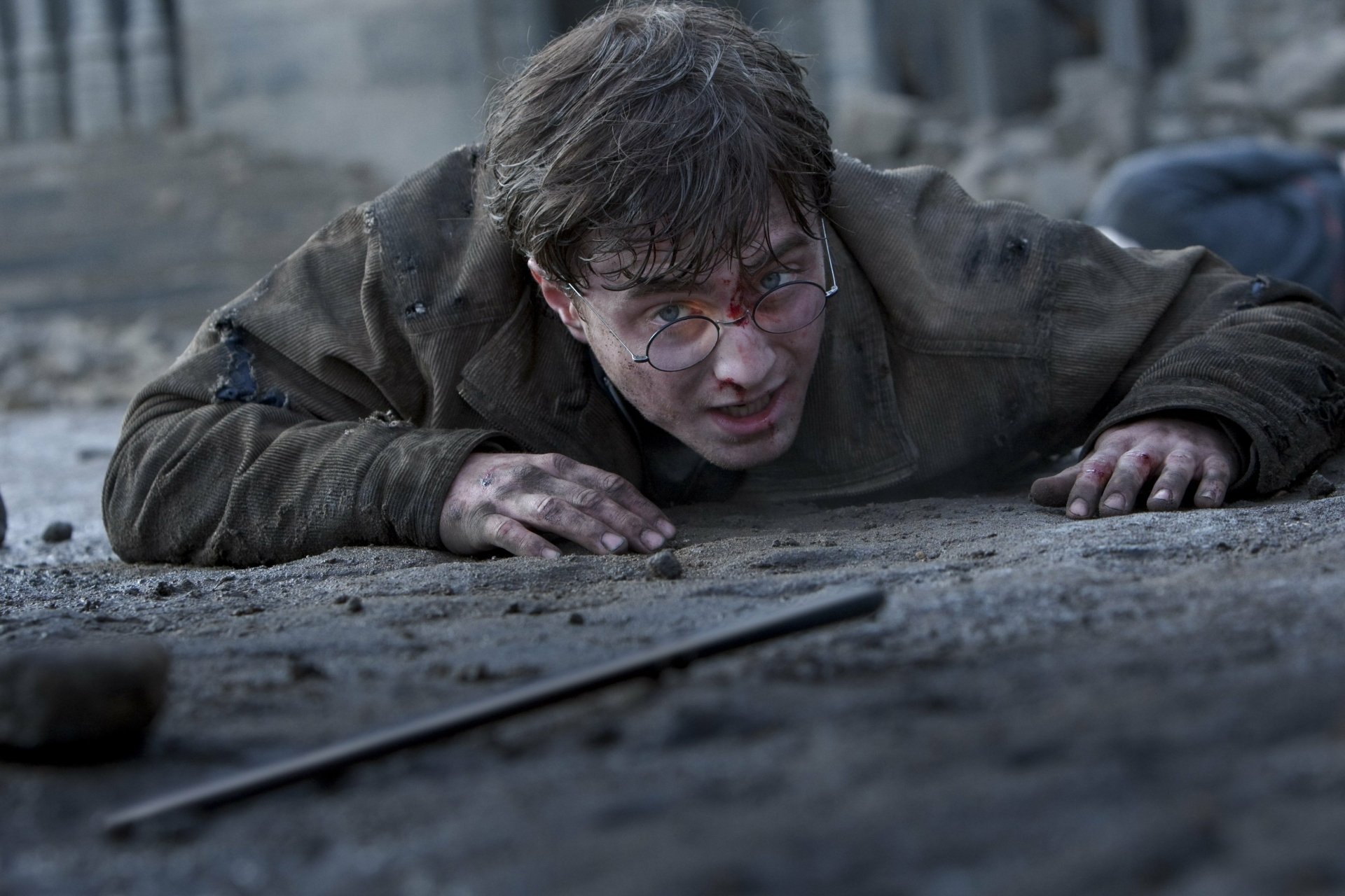 Harry Potter crawls across rubble, bloodied and exhausted — cinematic still from the movie Harry Potter and the Deathly Hallows: Part 2, 2K Quad HD PC desktop wallpaper/background.