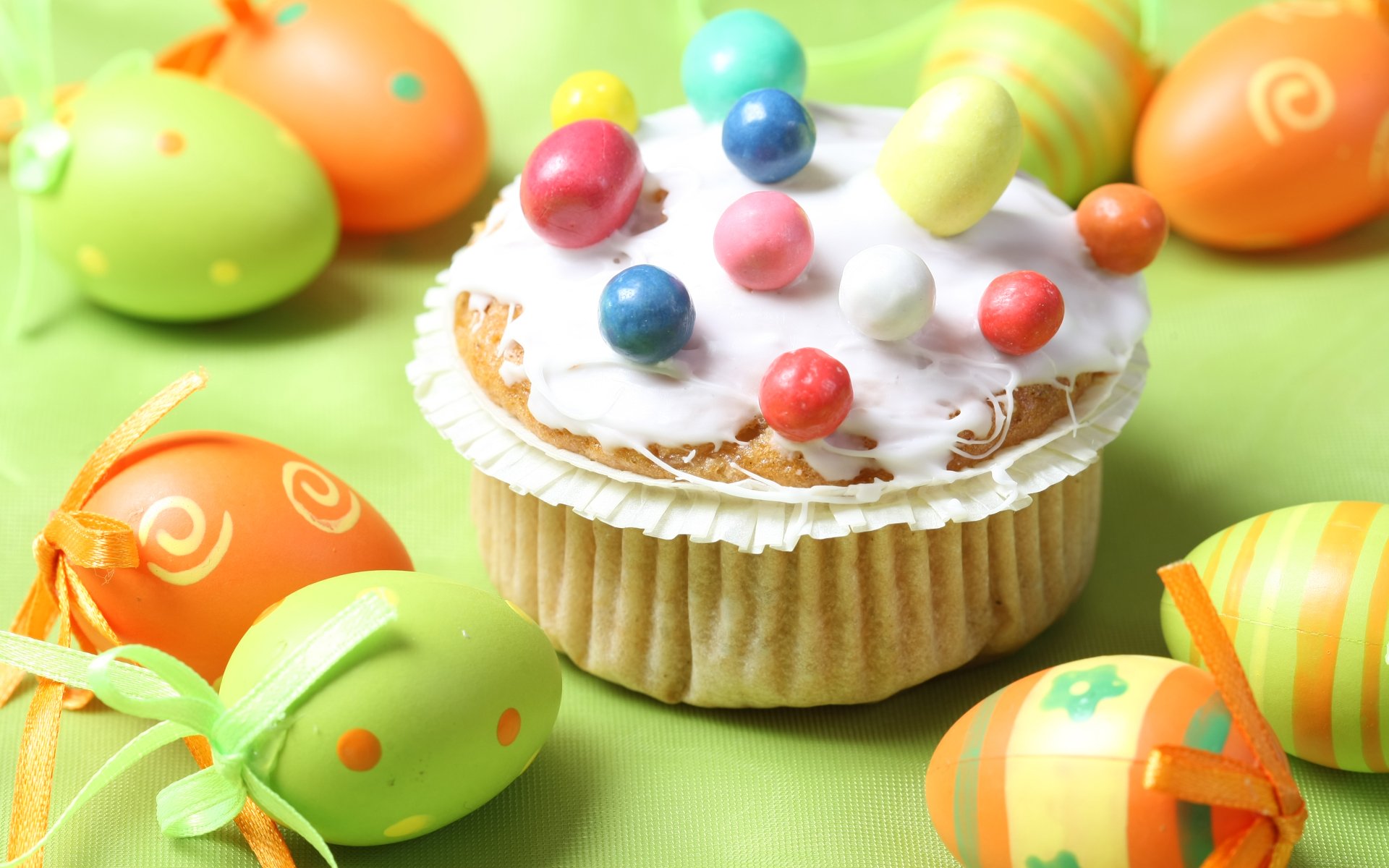 4K Ultra HD PC desktop wallpaper: holiday Easter cupcake with white icing and colorful candy beads, surrounded by bright painted eggs on a soft green background.