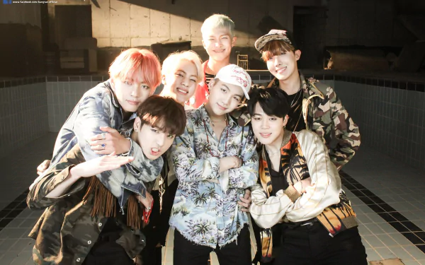 HD desktop wallpaper featuring the music group BTS. All seven members are grouped together, smiling and posing for the camera in a well-lit setting.