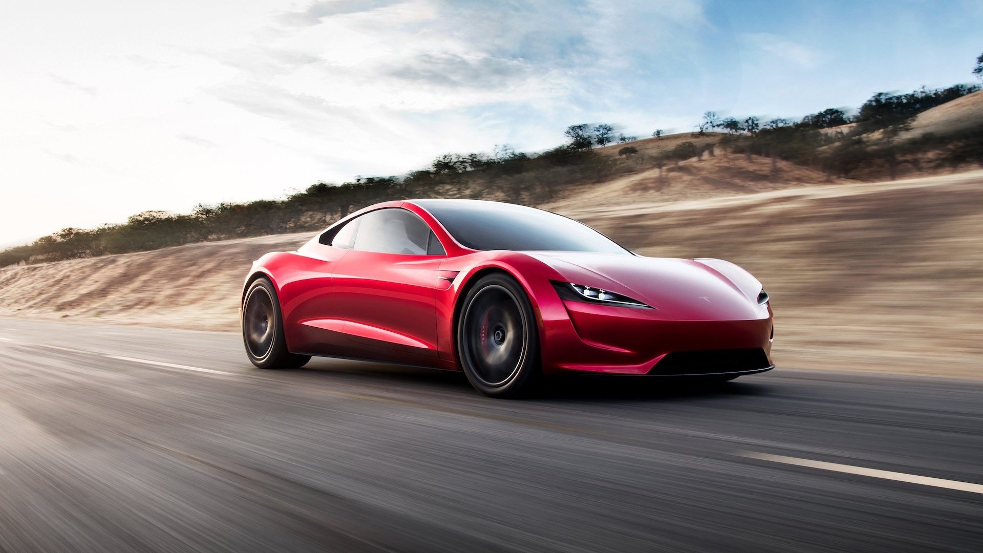 Red Tesla Roadster sports car by Tesla Motors speeding along a coastal highway — HD PC desktop wallpaper background.