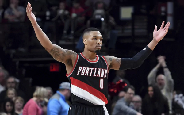 HD desktop wallpaper featuring basketball player Damian Lillard in a Portland jersey with arms outstretched during a game.