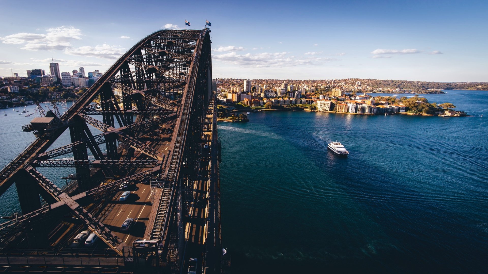 HD desktop wallpaper showcasing the iconic Sydney Harbour Bridge spanning the blue waters of Sydney, Australia, with city skyline and ferry in the background.