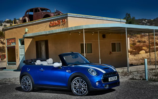 Blue Mini Cooper S convertible compact car parked before a vintage desert building, high-detail 4K Ultra HD PC desktop wallpaper background.