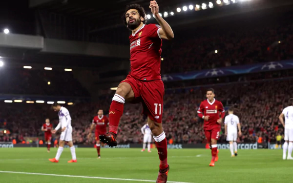 2K Quad HD PC desktop wallpaper: Egyptian soccer star in red kit leaping in celebration on a packed stadium pitch during a night match.
