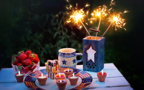 A festive 4th of July still life with sparklers, strawberries, star-decorated mugs, and candles, set as an HD PC desktop wallpaper celebrating Independence Day.