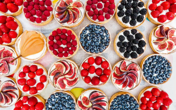 HD PC desktop wallpaper: overhead view of assorted berry and fig pastries — tarts topped with strawberries, raspberries, blackberries, blueberries and fig slices, colorful fruit desserts