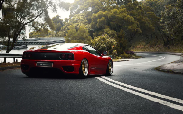 Red Ferrari 360 Modena supercar parked on a winding road surrounded by lush greenery, captured in high-definition for a sleek PC desktop wallpaper background.