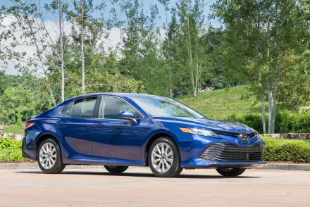 Blue Toyota Camry compact car parked on a tree-lined suburban street — 2K Quad HD PC desktop wallpaper background.