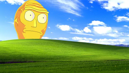 HD desktop wallpaper featuring a 'Rick and Morty' character's giant head against a lush green hill and a bright blue sky with fluffy clouds.