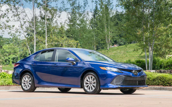 Blue Toyota Camry compact car parked on a tree-lined suburban street — 2K Quad HD PC desktop wallpaper background.