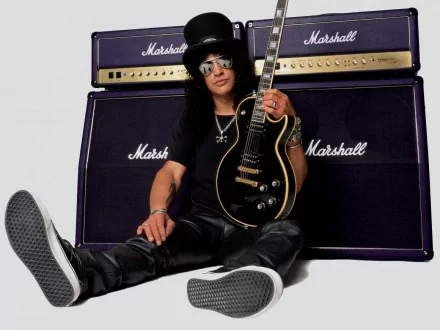 A high-definition desktop wallpaper featuring Slash, the iconic guitarist from Guns N' Roses, sitting with his guitar in front of Marshall amplifiers. A striking music-themed background.