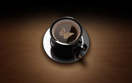 A high-definition desktop wallpaper featuring a cup of coffee with a butterfly shape in the foam, set against a wooden background.