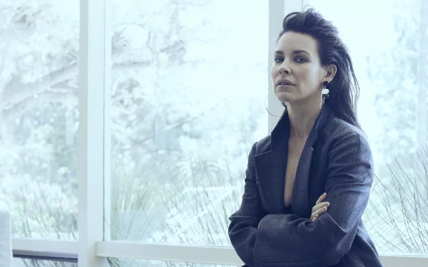 4K Ultra HD PC desktop wallpaper: poised female celebrity in a dark blazer stands by a bright window with arms crossed, gazing contemplatively.