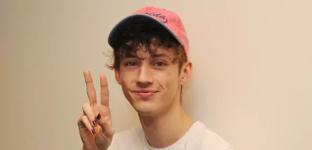 HD desktop wallpaper featuring a person posing with a peace sign, wearing a pink cap.
