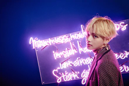 HD wallpaper of K-Pop singer V (Kim Tae-hyung) from BTS, posing against a backdrop of glowing neon text, radiating a cool and artistic vibe.
