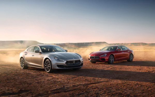 Silver and red Maserati Ghibli sedans on a dusty desert plain at sunset — 4K Ultra HD PC desktop wallpaper and background.