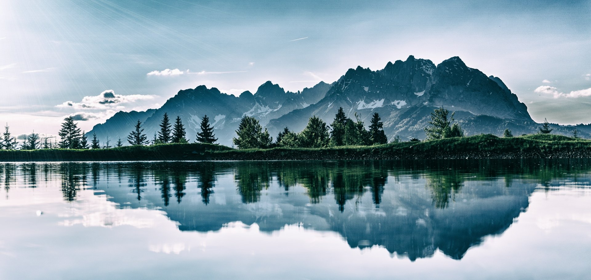 HD wallpaper of Bernardo O'Higgins National Park featuring serene mountain peaks reflected in a calm river, highlighted by twilight hues and silhouetted trees.