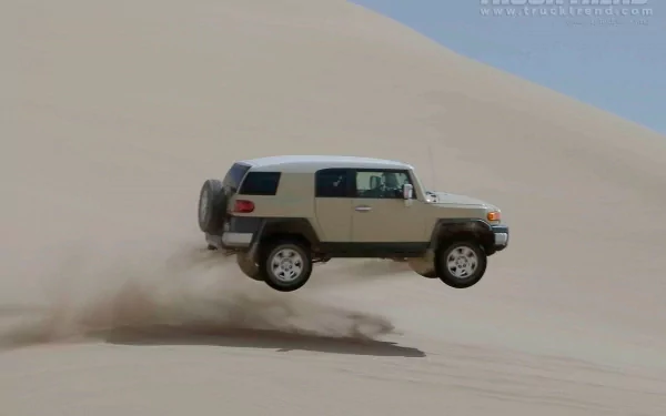 A Toyota FJ Cruiser airborne over sand dunes, captured in an HD desktop wallpaper showcasing rugged off-road adventure.
