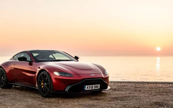 Red Aston Martin Vantage supercar on a shoreline at sunset — 4K Ultra HD PC desktop wallpaper showing the coupe reflecting golden light.