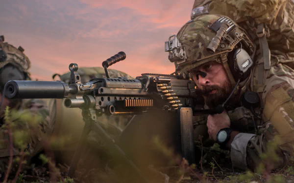 Camouflaged soldier prone operating a belt-fed machine gun at sunset — military scene, 5K Ultra HD PC desktop wallpaper/background