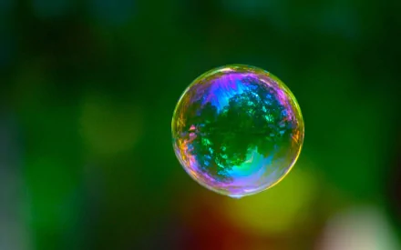A colorful soap bubble floats against a vibrant green background, captured in high definition, creating a stunning visual for a desktop wallpaper.