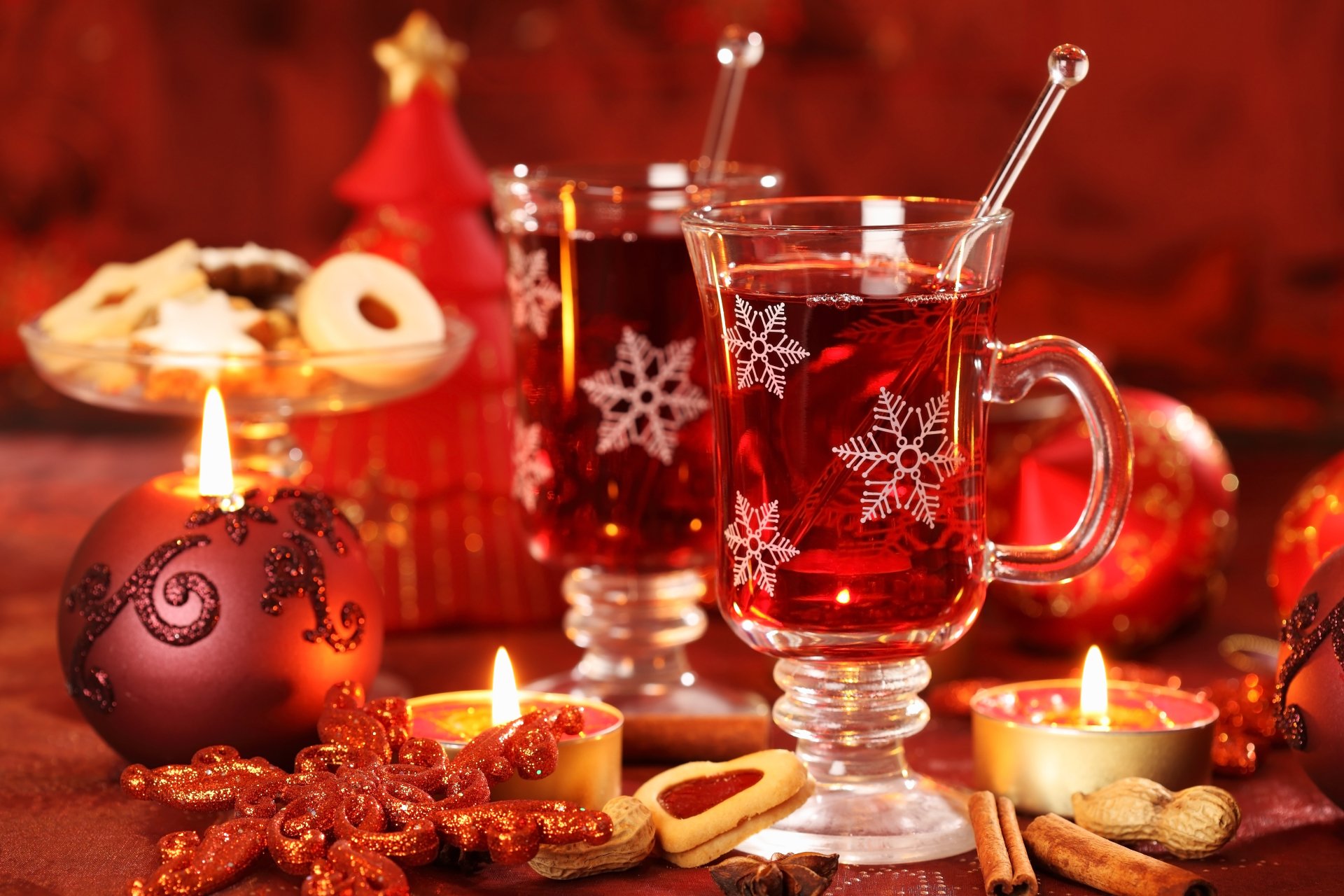 HD desktop wallpaper featuring warm Christmas tea in clear mugs, surrounded by lit candles, Christmas ornaments, and festive cookies.