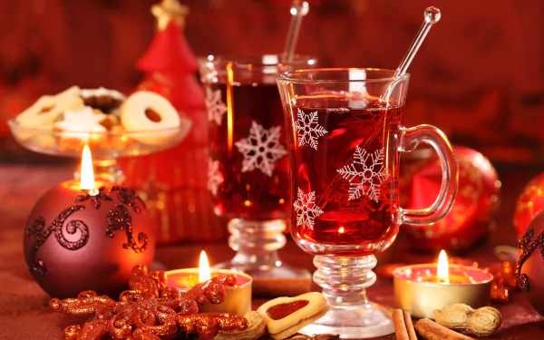 HD desktop wallpaper featuring warm Christmas tea in clear mugs, surrounded by lit candles, Christmas ornaments, and festive cookies.