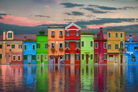 Vibrant, colorful man-made houses reflected in calm water under a dramatic sky, captured in stunning 4K Ultra HD as a vivid PC desktop wallpaper.