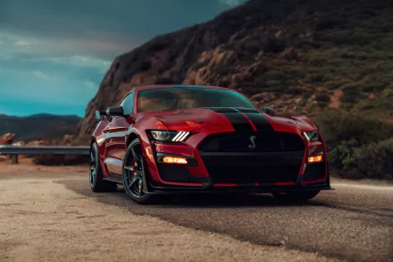 A red Ford Mustang Shelby GT500 muscle car with black racing stripes parked on a desert road, captured in 8K Ultra HD for PC desktop wallpaper.