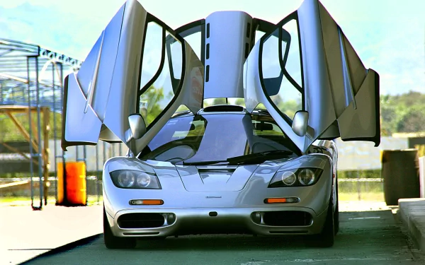 HD PC desktop wallpaper featuring a silver McLaren F1 with its iconic butterfly doors open in a garage setting.