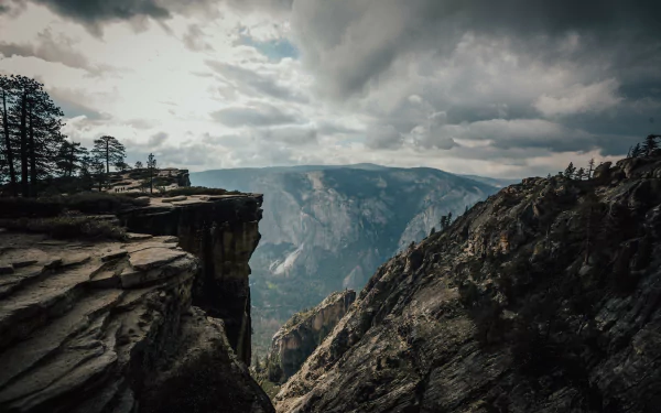 Dramatic view of rocky cliffs and cloudy skies in Yosemite National Park, captured in stunning 4K Ultra HD for a nature-themed PC desktop wallpaper.