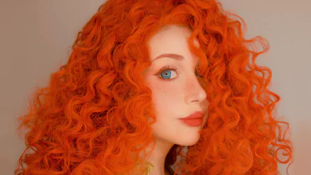 Cosplay of Merida from Brave, featuring a woman with vibrant, curly orange hair and striking blue eyes. This high-definition image serves as a captivating desktop wallpaper.
