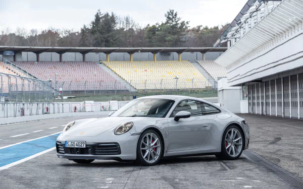 Silver Porsche 911 Carrera on a racetrack pit lane, front three-quarter view; 4K Ultra HD PC desktop wallpaper and background.