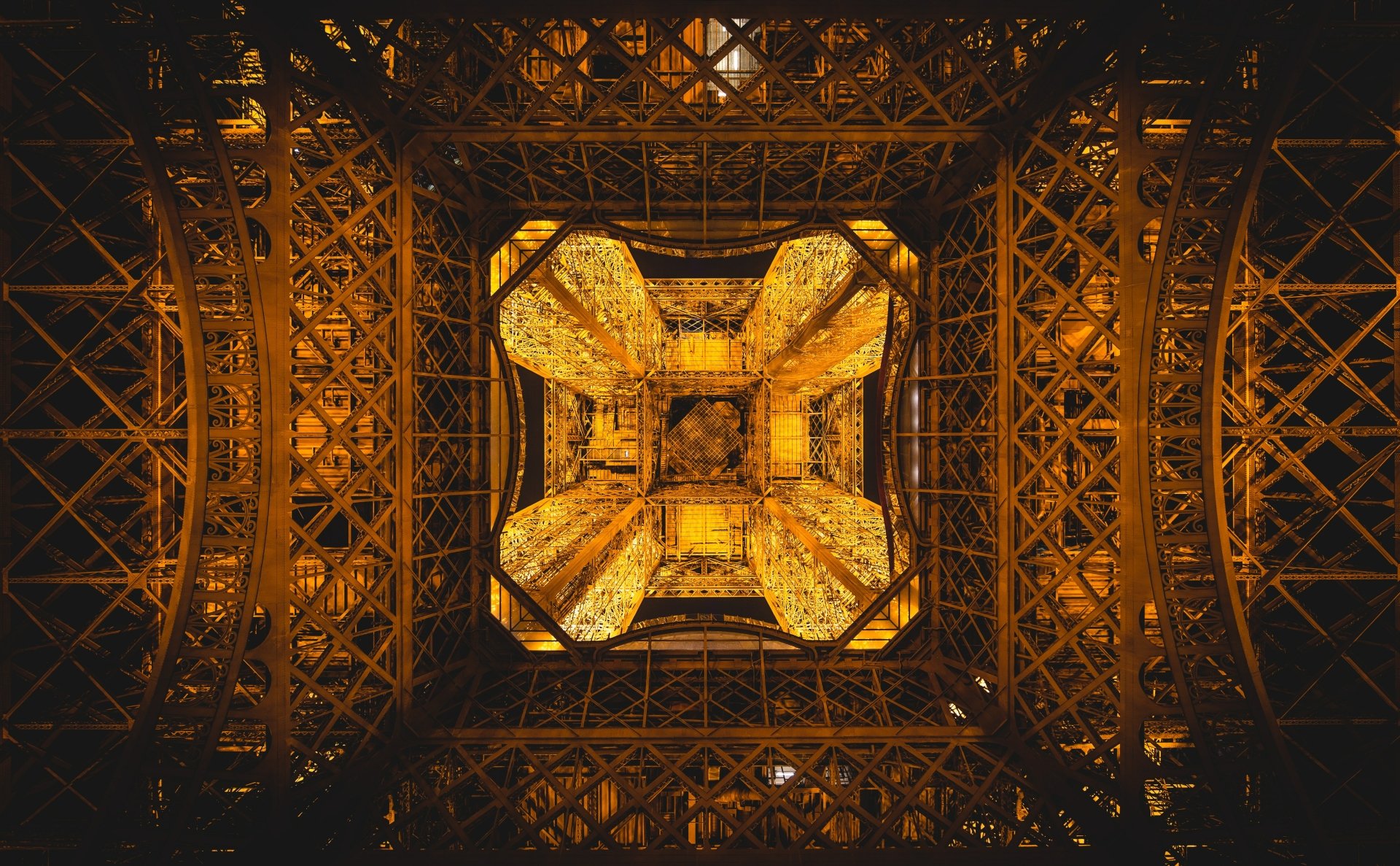 4K Ultra HD view from beneath the illuminated Eiffel Tower, showcasing intricate man-made architecture in Paris, France.