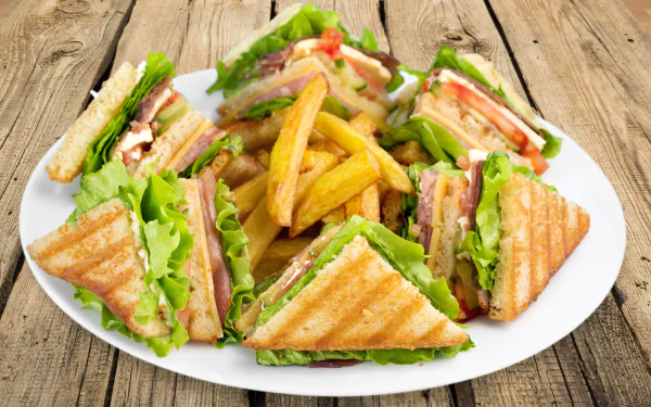 4K Ultra HD PC desktop wallpaper background: plate of sandwich wedges and golden french fries on a rustic wooden surface — food close-up.