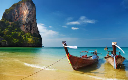 A serene beach scene featuring two canoes anchored in clear turquoise waters, with a lush green cliff in the background, captured in stunning 4K Ultra HD quality.