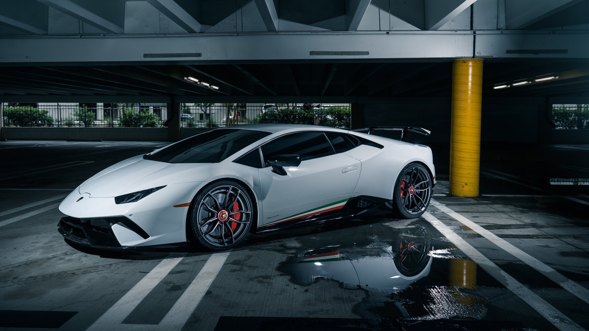 White Lamborghini Huracan Performante supercar parked in a dim, wet parking garage with reflections — 4K Ultra HD PC desktop wallpaper/background.