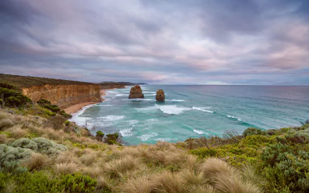 HD wallpaper of The Twelve Apostles along the rugged coastline of Victoria, Australia, showcasing the ocean and natural landscape under a cloudy sky.