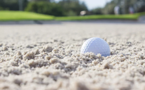 Close-up of a golf ball nestled in sand on a golf course, captured in 4K Ultra HD for a detailed PC desktop wallpaper background.