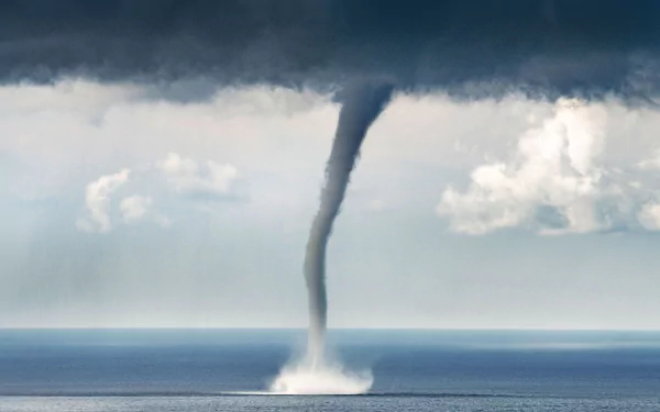 HD PC desktop wallpaper: dramatic waterspout over the ocean, sea spray rising beneath dark storm clouds in a raw nature scene.